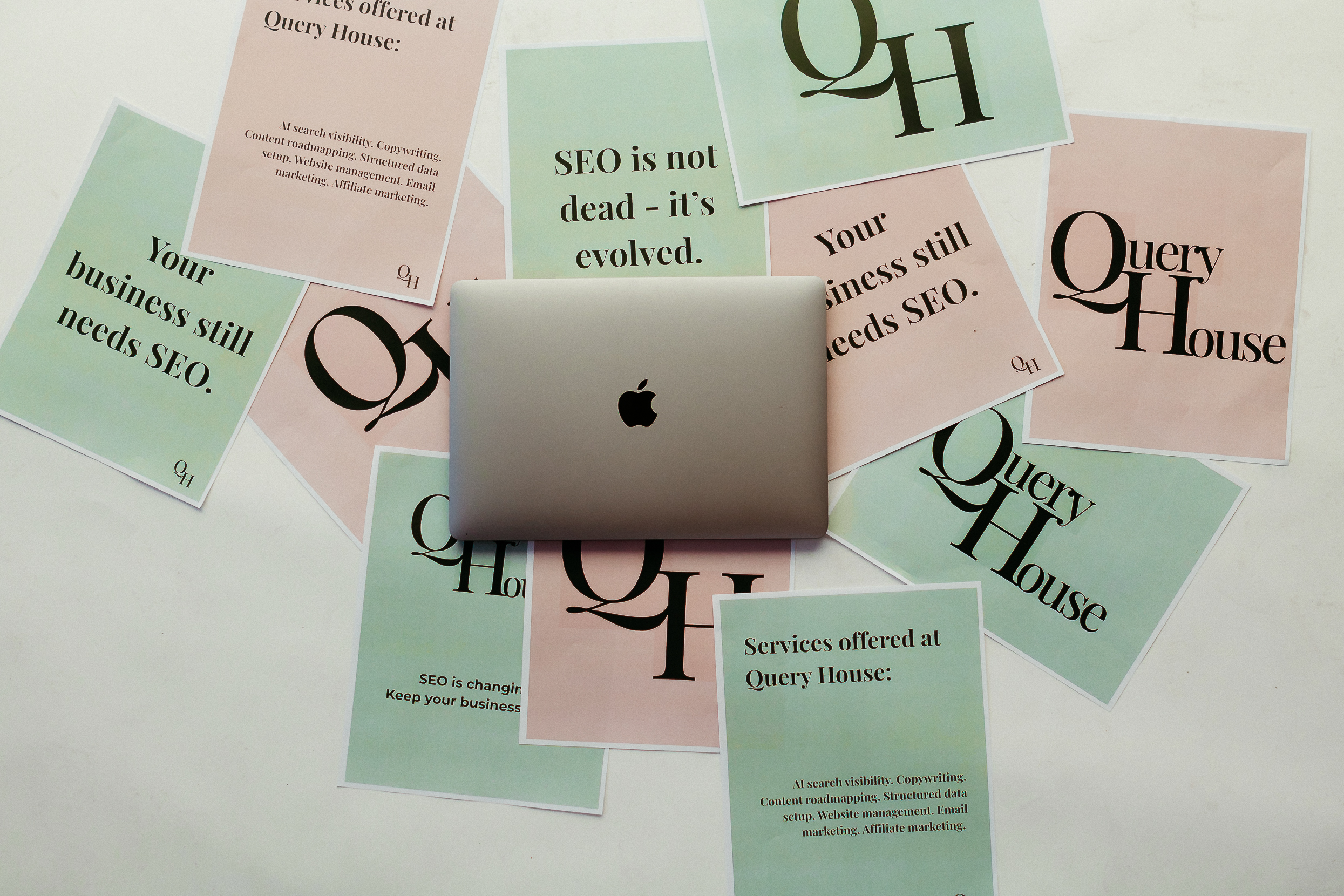 Query House Marketing services on pink and green paper with laptop